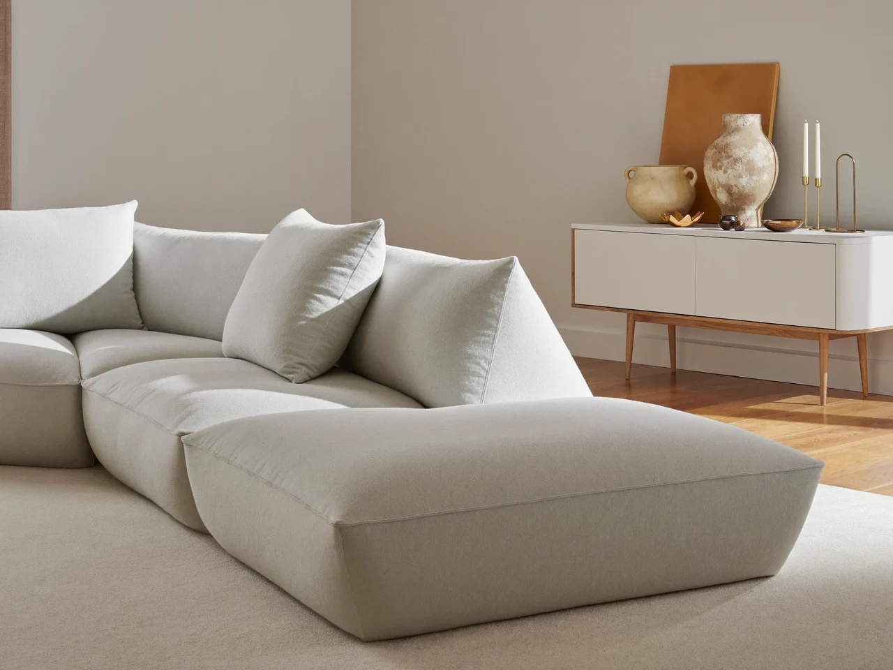 Helle Wohnzimmerecke mit Sofa und Sideboard, dekoriert mit Keramik und Messing