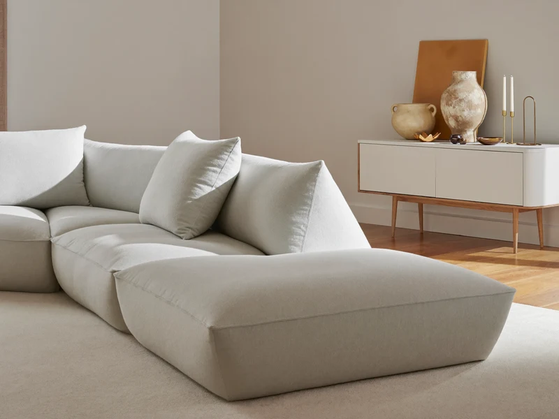 Helle Wohnzimmerecke mit Sofa und Sideboard, dekoriert mit Keramik und Messing